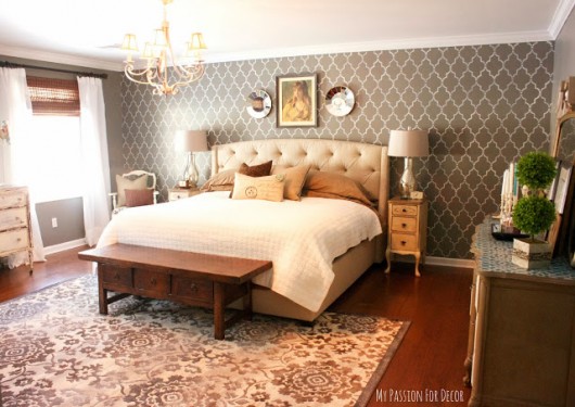 A gray DIY stenciled accent wall in a master bedroom using the Marrakech Trellis Stencil from Cutting Edge Stencils.