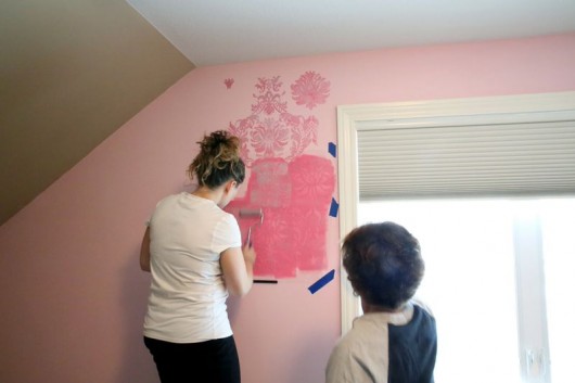 Stenciling a pink and teal stenciled accent wall in a nursery using the Gabrielle Damask pattern.. http://www.cuttingedgestencils.com/damask-stencil-3.html