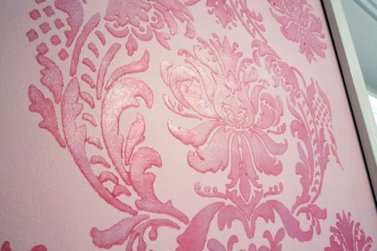 Stenciling a pink and teal stenciled accent wall in a nursery using the Gabrielle Damask pattern.. http://www.cuttingedgestencils.com/damask-stencil-3.html