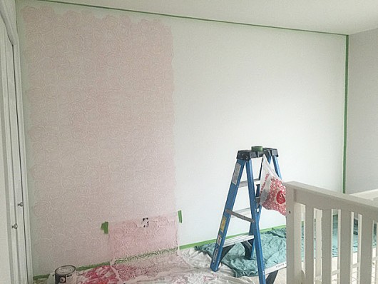 Stenciling a DIY accent wall in a nursery using the Roses Allover Stencil in light pink and white. http://www.cuttingedgestencils.com/roses-stencil-pattern-rose-design.html