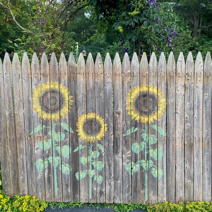 Large sunflowers stenciled on a wooden fence